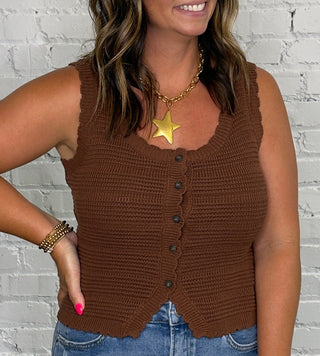 A woman modeling a brown ribbed sleeveless vest top with button details, paired with light blue jeans.