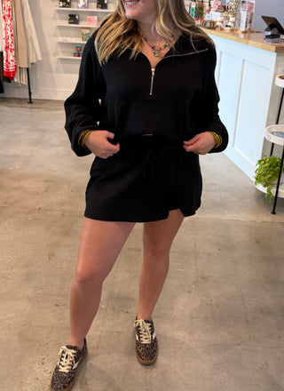 women wearing a black quarter zip with a matching skort