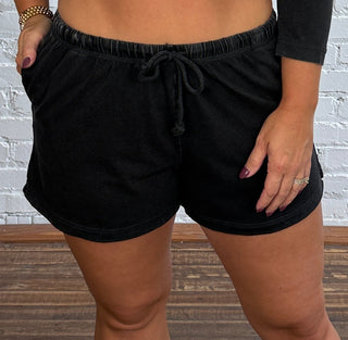 Women wearing a casual matching black set with colorful necklace and butter yellow tennis shoes.
