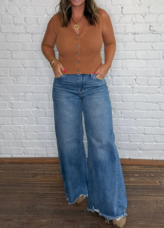 Fitted tan ribbed knit top and high-waisted, wide-leg blue jeans with raw hems.
