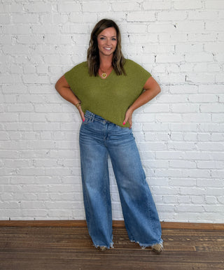 Short-sleeve olive green top and wide-leg blue jeans.