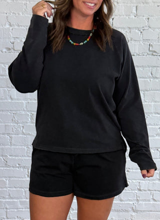 Women wearing a casual matching black set with colorful necklace and butter yellow tennis shoes.