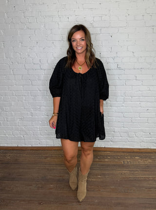Black eyelet short-sleeve romper and beige suede ankle boots.