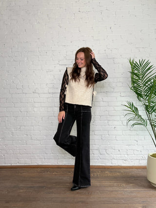 Woman posing in a room with a white brick wall and a plant.