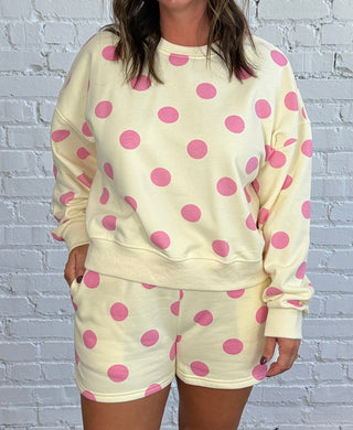 Women wearing a cream matching set with pink polka dots paired with butter yellow tennis shoes.