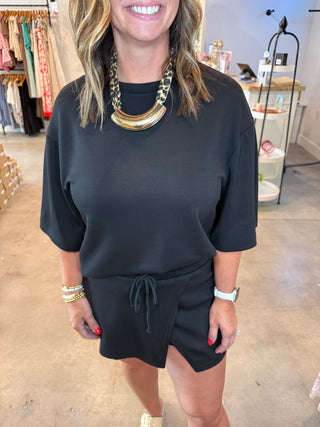 Person wearing a black outfit with gold accents