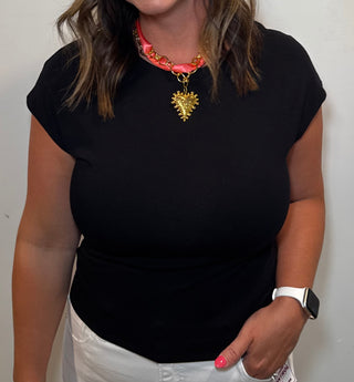 Woman wearing a black top and white pants against a plain background