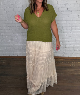 Olive green knit top paired with a long cream pleated, lace skirt.