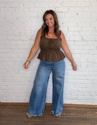 Brown sleeveless peplum top and wide-leg blue jeans.