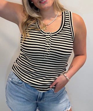 Women wearing a bkack and cream striped tp with button detail and denim shorts