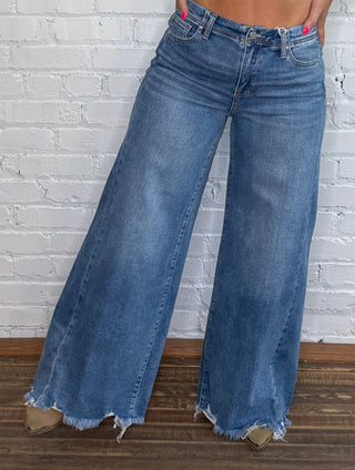 Wide-leg blue jeans with frayed hems.