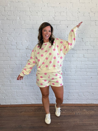 Women wearing a cream matching set with pink polka dots paired with butter yellow tennis shoes.