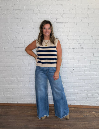 Sleeveless beige top with navy horizontal stripes and wide-leg blue jeans.