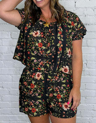 A woman modeling a black short-sleeve matching set with a colorful floral print.