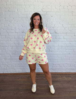 Women wearing a cream matching set with pink polka dots paired with butter yellow tennis shoes.