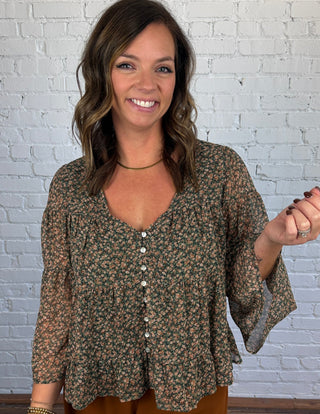 Women wearing brown pants paired with a teal and brown floral flowy top and boots.