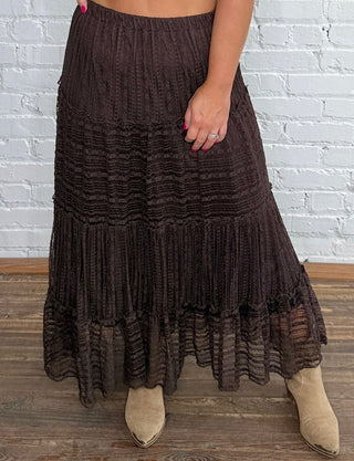 A woman modeling a dark brown tiered lace midi skirt with a smocked waistband, paired with taupe boots.