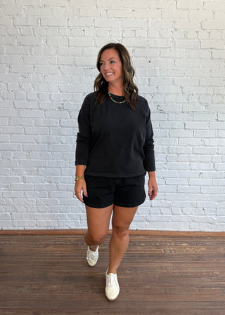 Women wearing a casual matching black set with colorful necklace and butter yellow tennis shoes.
