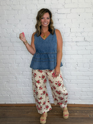 Sleeveless blue denim peplum top and cream wide-leg pants with a red floral pattern.