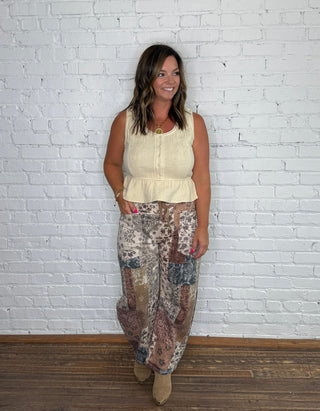 Sleeveless , embroidered cream top and patterned barrel jeans.