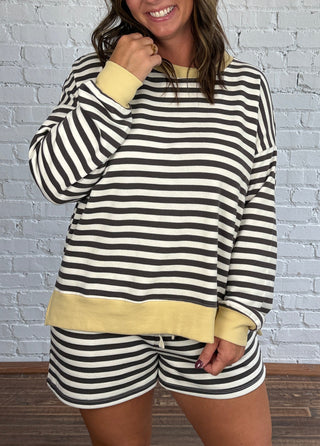 Women wearing a charcoal and cream striped casual matching set with butter yellow hem and tennis shoes.