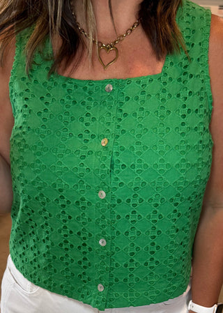 Woman wearing a green sleeveless top and white pants 