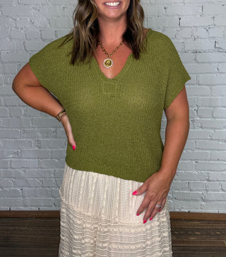 Textured olive green short-sleeve top and a cream pleated maxi skirt.