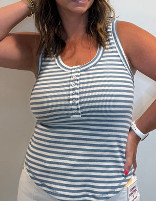 Woman wearing a striped blue and white tank top and white pants.