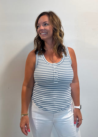 Woman wearing a blue and white striped tank top and white pants.
