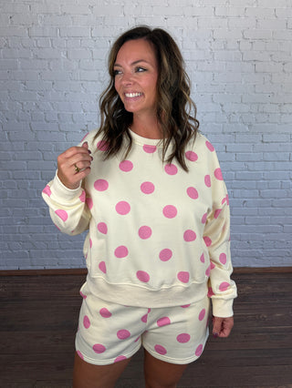 Women wearing a cream matching set with pink polka dots paired with butter yellow tennis shoes.