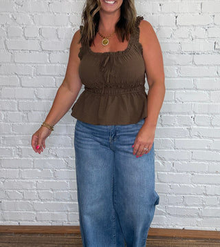 Brown sleeveless ruffle-trimmed top and wide-leg blue jeans.