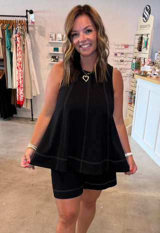 Woman in a black matching set wtih white stitching