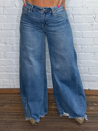Wide-leg blue jeans with raw hem.