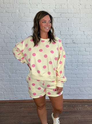 Women wearing a cream matching set with pink polka dots paired with butter yellow tennis shoes.