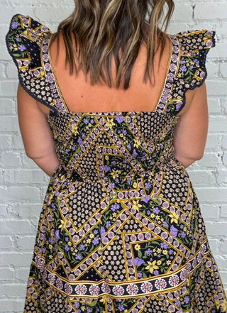back view of a short sleeve midi dress with pockets featuring a navy, purple, orange, green and yellow geometric pattern.