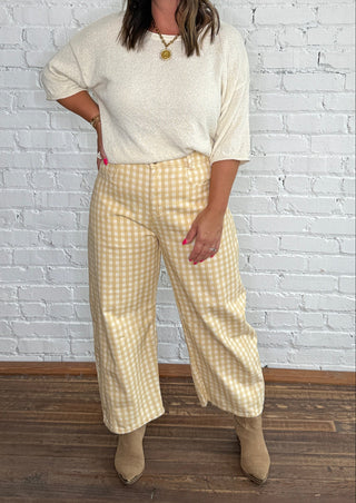Cream knit top and yellow-and-white gingham barrel jeans with tan ankle boots.