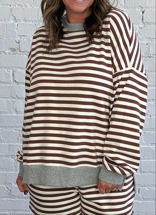 Women wearing a casual chocolate brown and cream striped matching set with a gray hem.