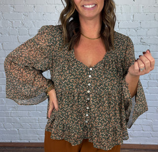 Women wearing brown pants paired with a teal and brown floral flowy top and boots.