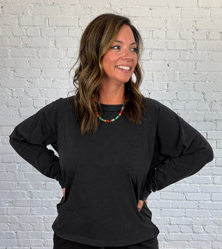 Women wearing a casual matching black set with colorful necklace and butter yellow tennis shoes.