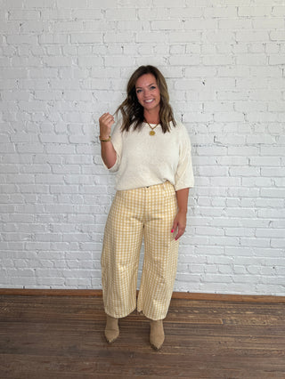 Cream knit sweater and yellow-and-white gingham barrel jeans with tan ankle boots.
