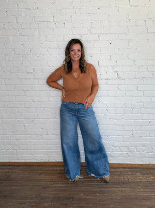 Fitted chestnut button-down top and wide-leg blue jeans.