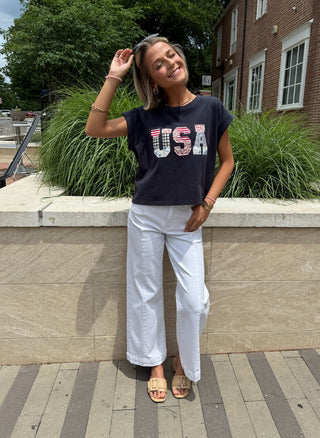 Woman wearing a navy 'USA' shirt and white denim jeans
