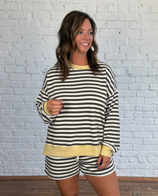 Women wearing a charcoal and cream striped casual matching set with butter yellow hem and tennis shoes.