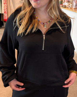 Woman wearing a black quarter zip with matching skort