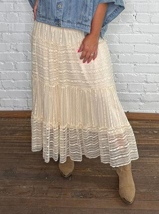 Denim jacket and a tiered, lace cream midi skirt.