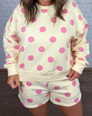 Women wearing a cream matching set with pink polka dots paired with butter yellow tennis shoes.