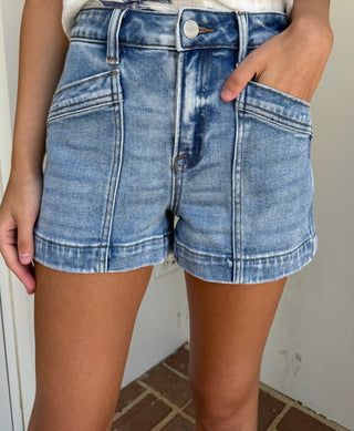 Person wearing blue denim shorts with a white background