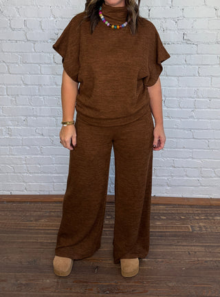 Woman wearing a micro ribbed brown, matching set and colorful beaded necklace.