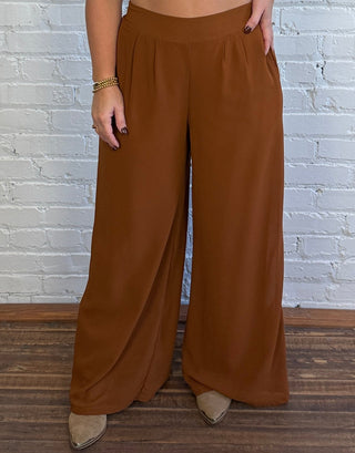 Woman wearing a pair of brown trousers and styled with top boots.