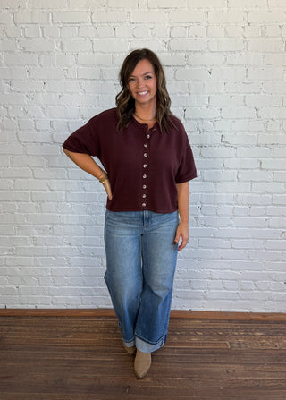 Women wearing in a button of short sleeve sweater with denim and top boots.